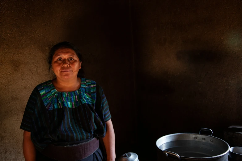 a person standing next to an open cooking pan and two pots on the stove