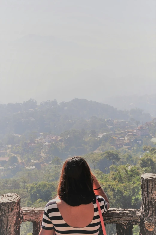 a girl wearing a striped shirt is looking out over a town