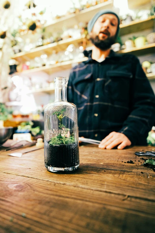 a person standing next to a bottle filled with plants