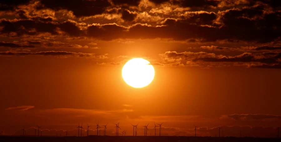 an orange and yellow sun shining through some clouds