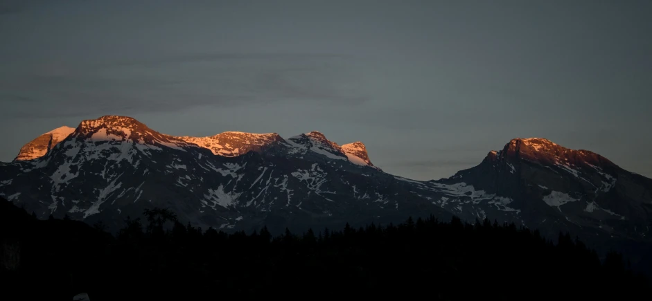 the sunset lights up a snowy mountain range