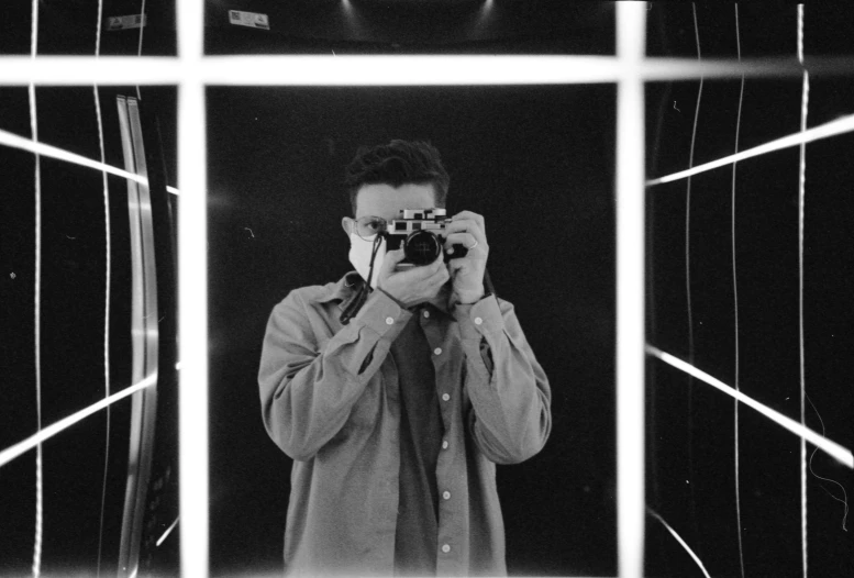 a man holding up a camera while looking in a mirror