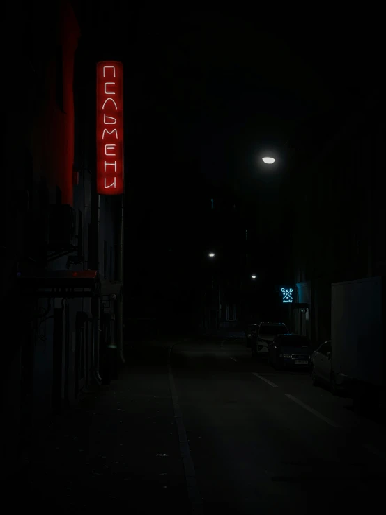 a dark road with street lights and signs in the distance