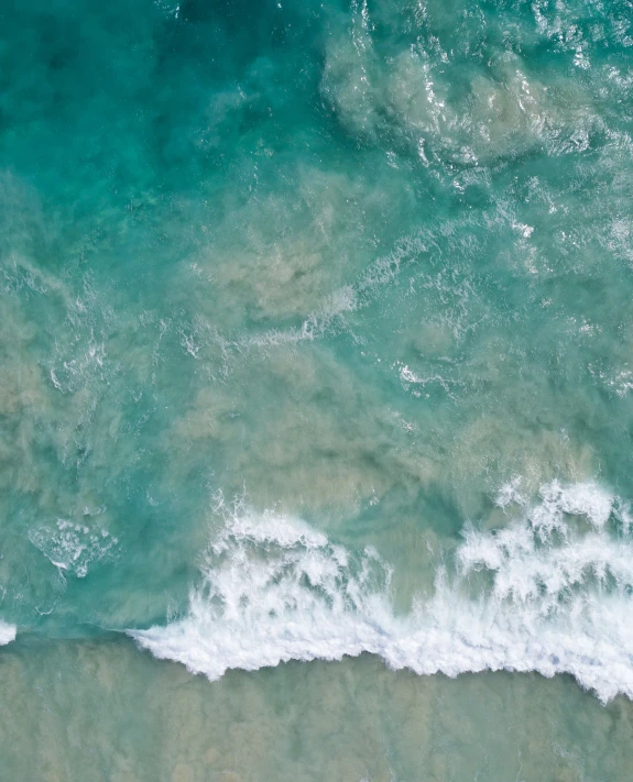 a person stands on a wave of water on top of the sand