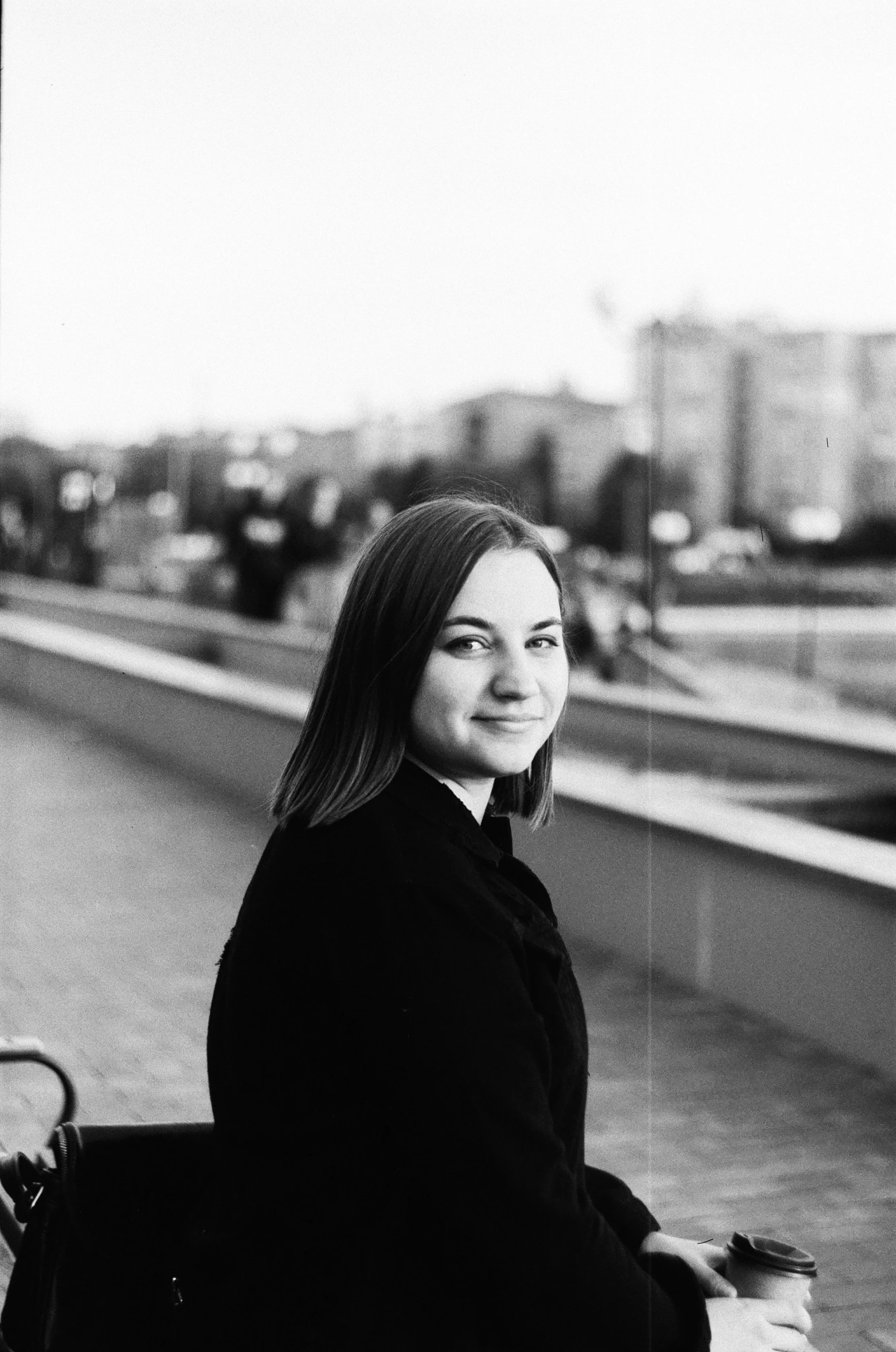 a girl in a black coat sitting on a bench