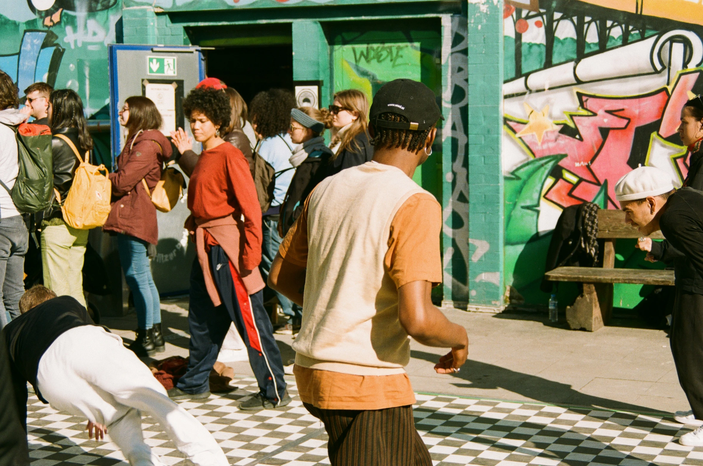 there are many people standing next to a graffiti wall