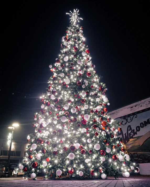 a large christmas tree lit up and decorated in red, white, and silver