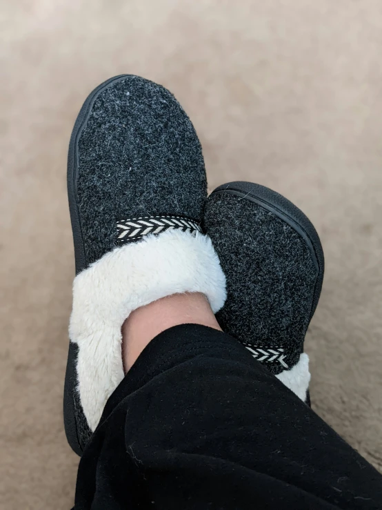 a person is wearing black slippers with white sherpole