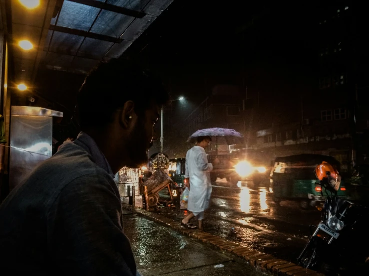 a man in white jacket standing under umbrella on street