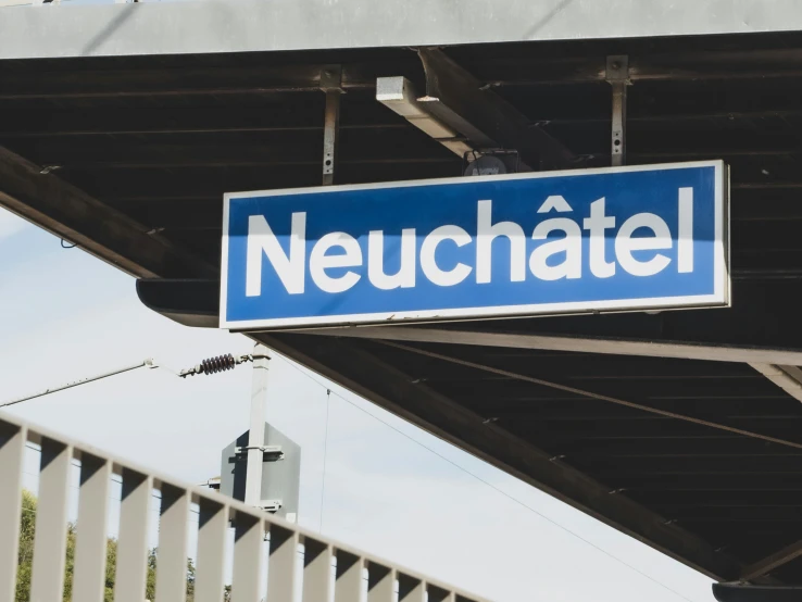 a blue sign is mounted under an overpass