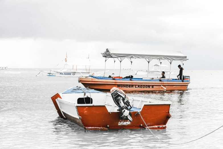 two small boats in the ocean with people standing on top