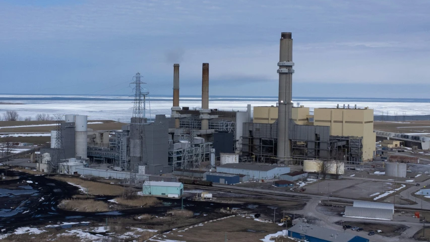 an industrial area with a snow covered field, industrial buildings and industrial water pipes