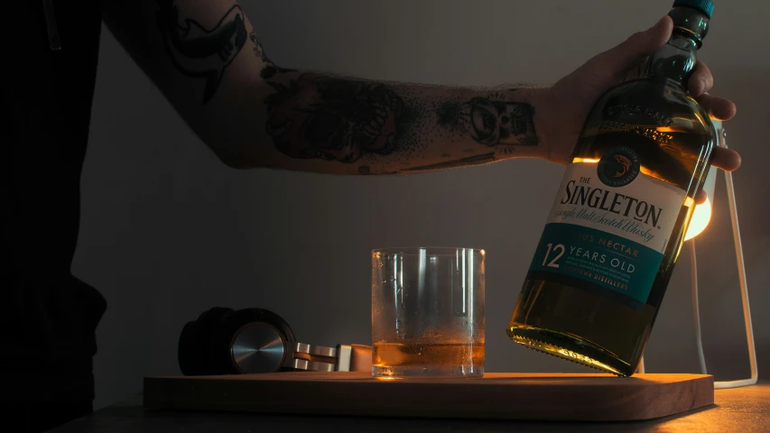 a man's arm is decorated with tattoos and holding a bottle of whisky