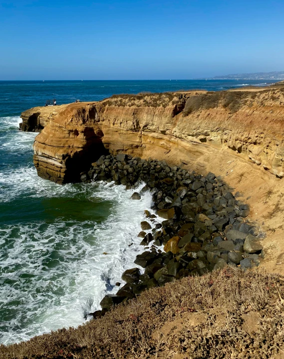 an ocean landscape with a rocky cliff on the shore