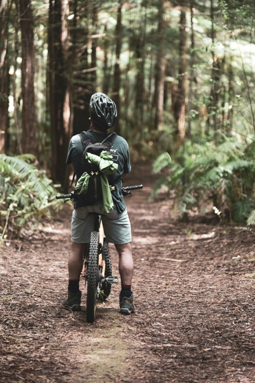 a man holding his bike in the woods