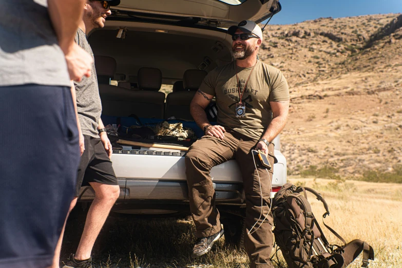 two people standing and sitting near a van with the door open