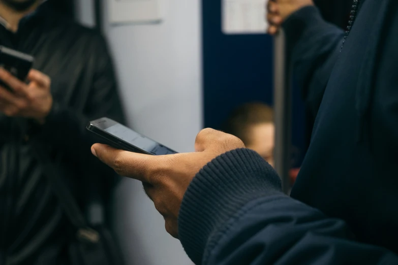 a man using a phone while standing in a room with other people