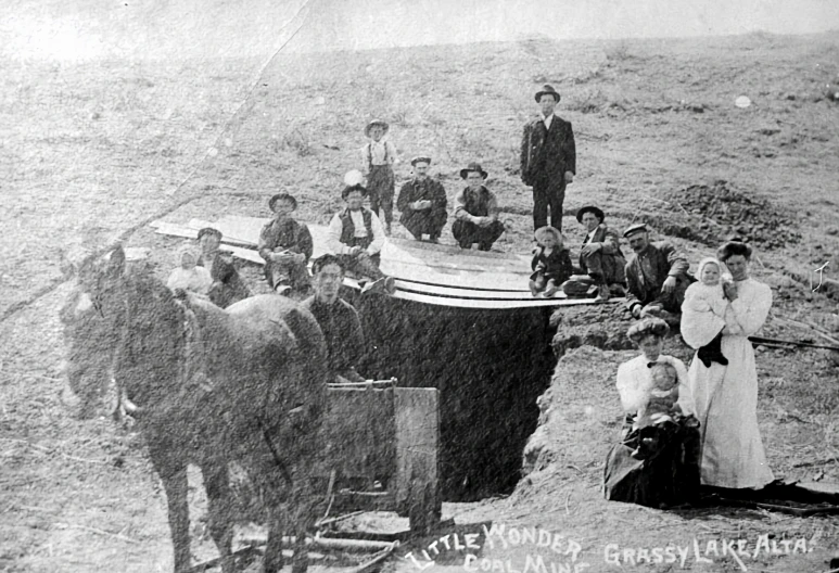 this black and white po shows an old farm scene with people around a boat on the shore