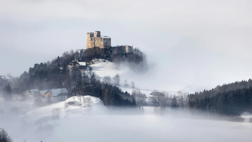 a hill covered in fog next to some trees