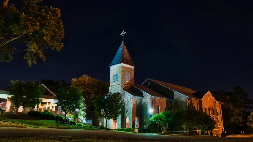 an old church lit up at night with the spire illuminated up