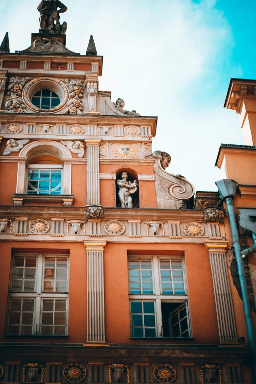 an orange building with statues on the front of it