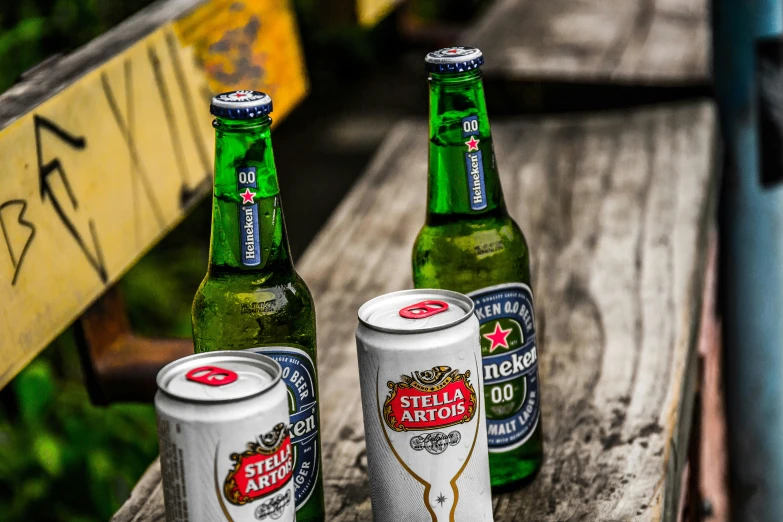 a couple of bottles of beer sitting on top of a wooden bench