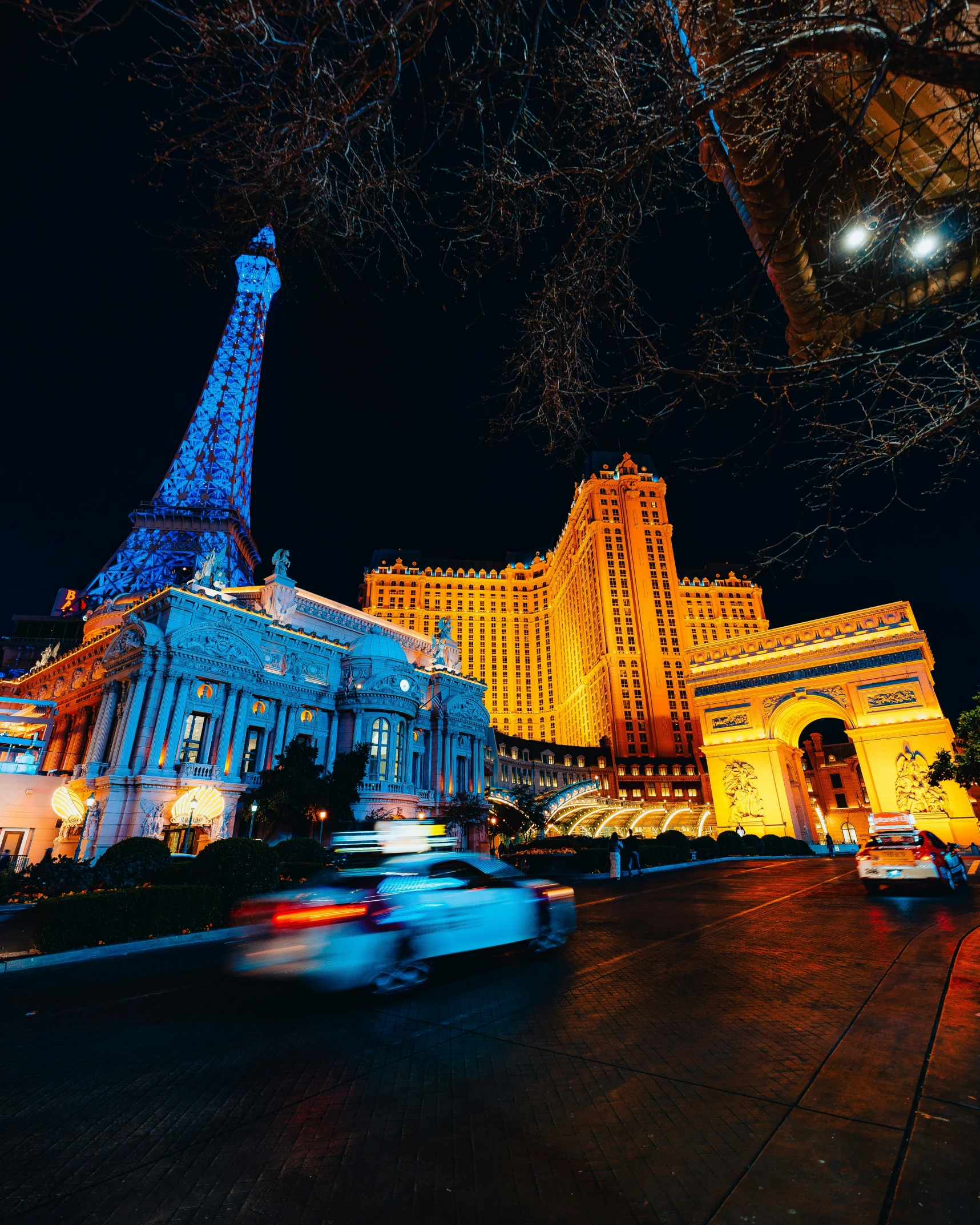 eiffel tower lit up at night with traffic passing by