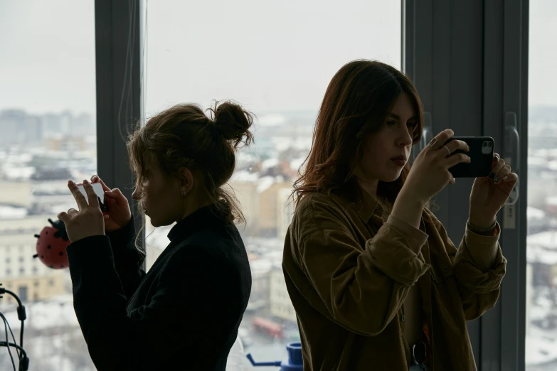 two girls standing next to each other while taking pos with their cameras