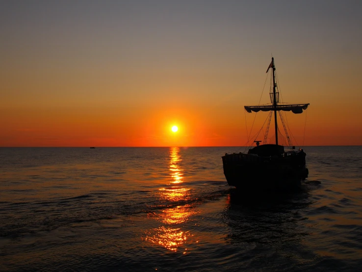 a boat is sailing in the water as the sun sets