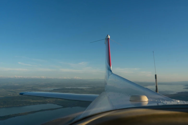 a jet flying over the water under a blue sky