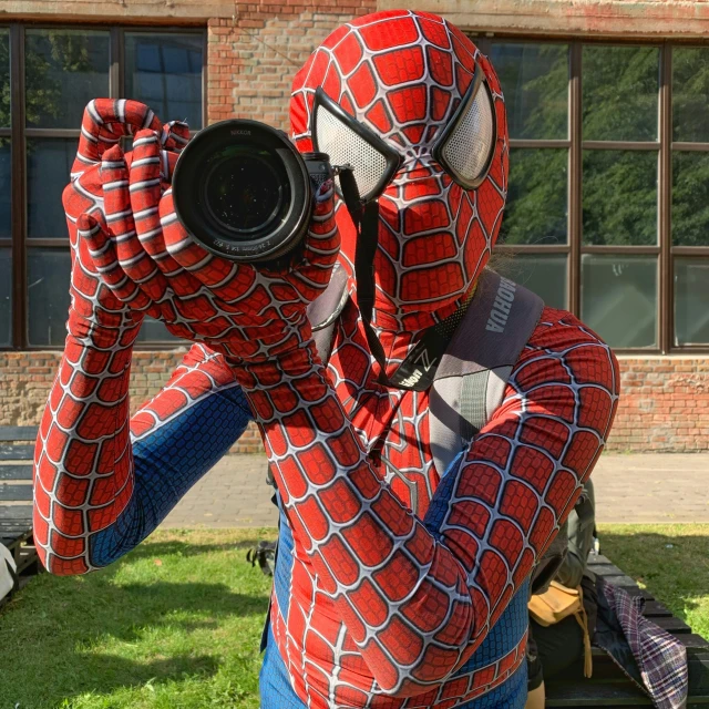 a man wearing a spiderman suit takes a po