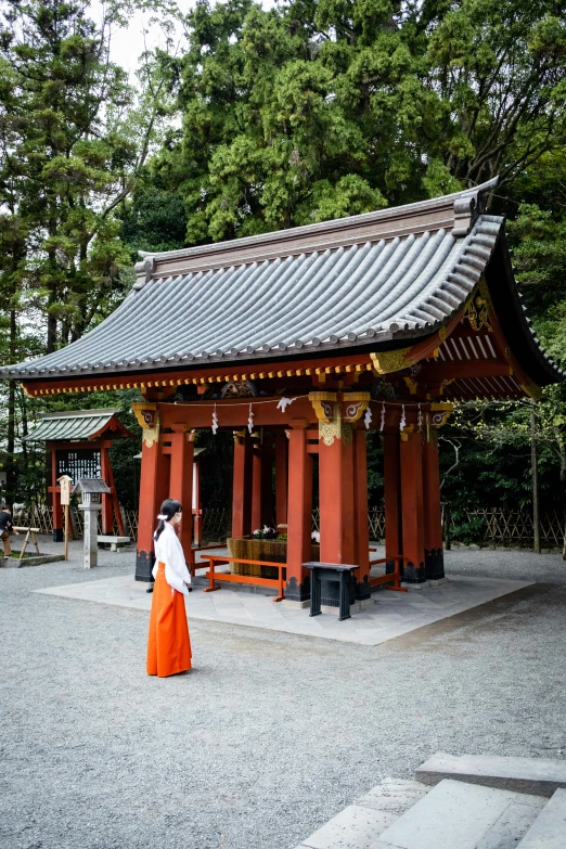 a woman in an orange dress stands near a pavilion