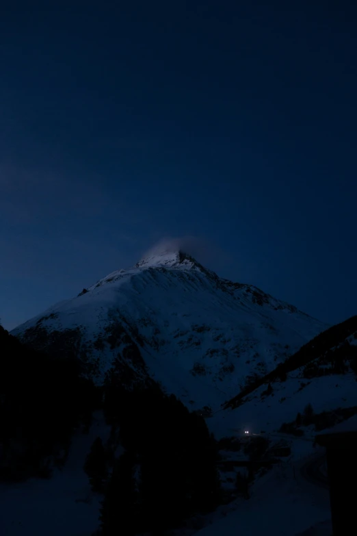 a snow - capped mountain is lit up at night