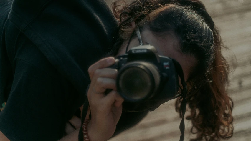 a woman with long curly hair taking a po with her camera