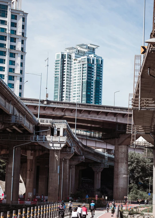 pedestrians walking under a busy bridge in the city