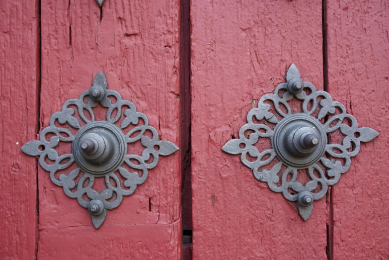 two iron door knockets on a red painted wooden door