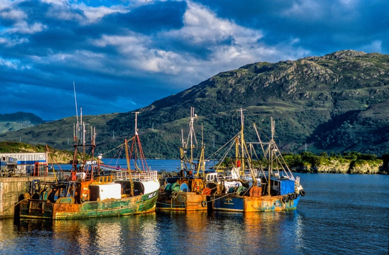 several boats that are in the water next to a mountain