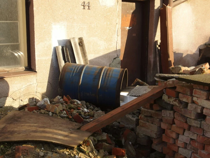 a rusty metal barrel sitting next to a broken down building