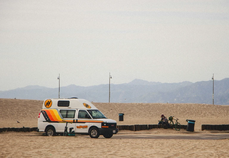 an ambulance parked in a sandy field with some people