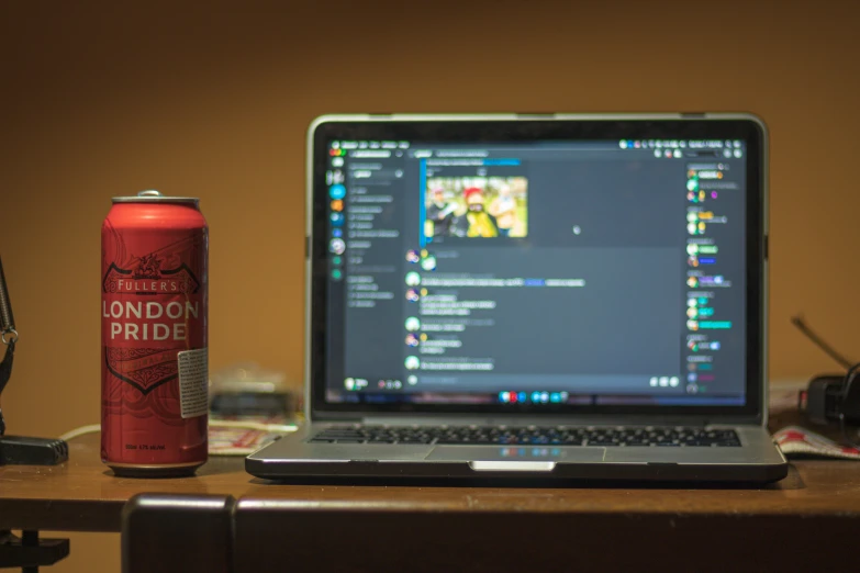 the laptop is beside the beverage can on the desk