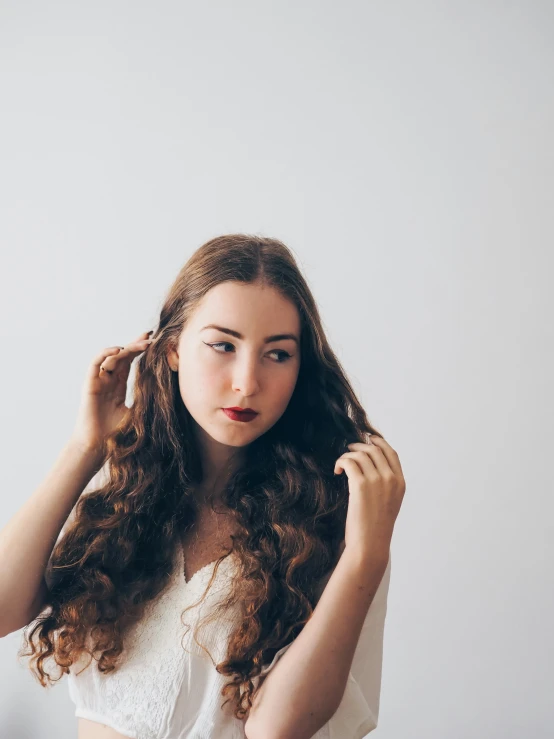 a woman holding a hair piece while wearing a 