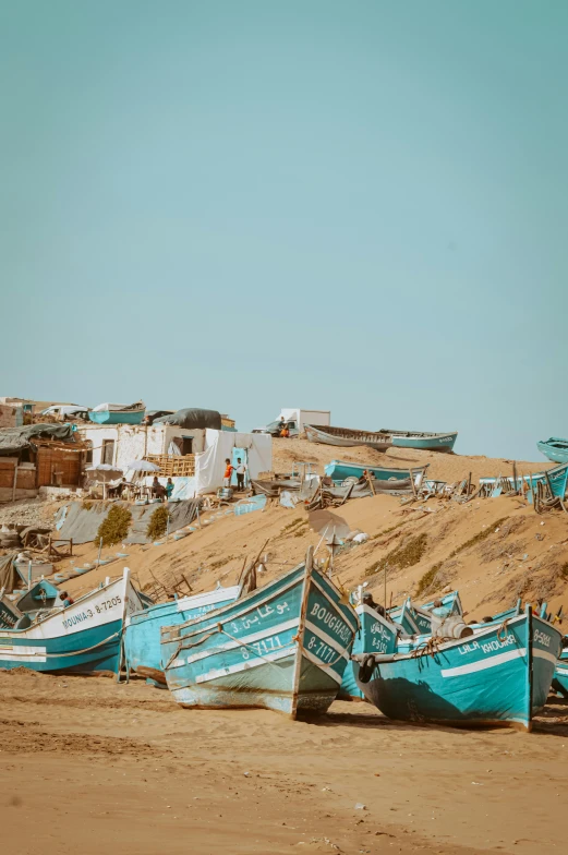 a bunch of blue boats are on a sandy beach