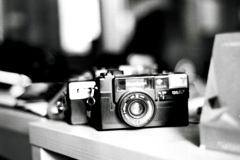 a old camera sits on the counter in front of another camera