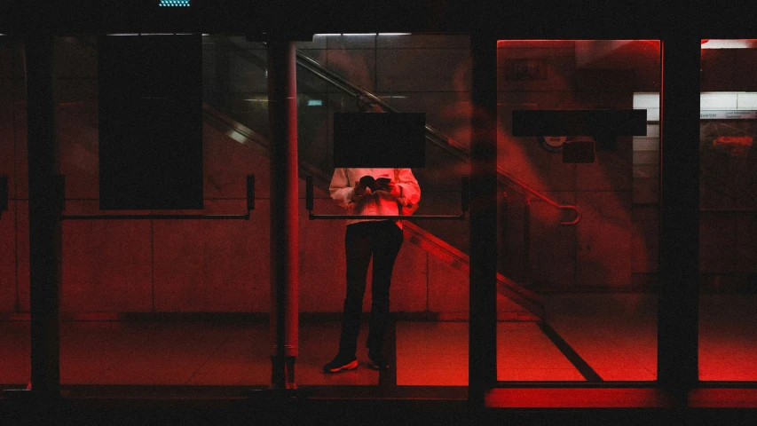 a man stands at a doorway while using a red light
