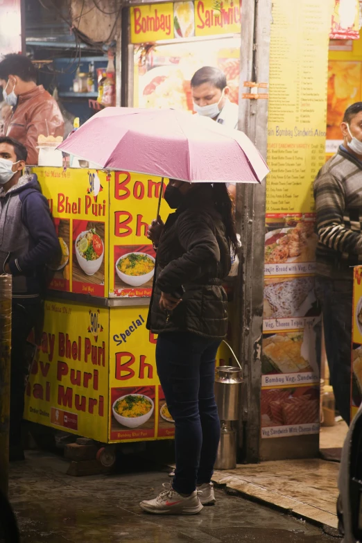 a woman with an umbrella stands near some food stands