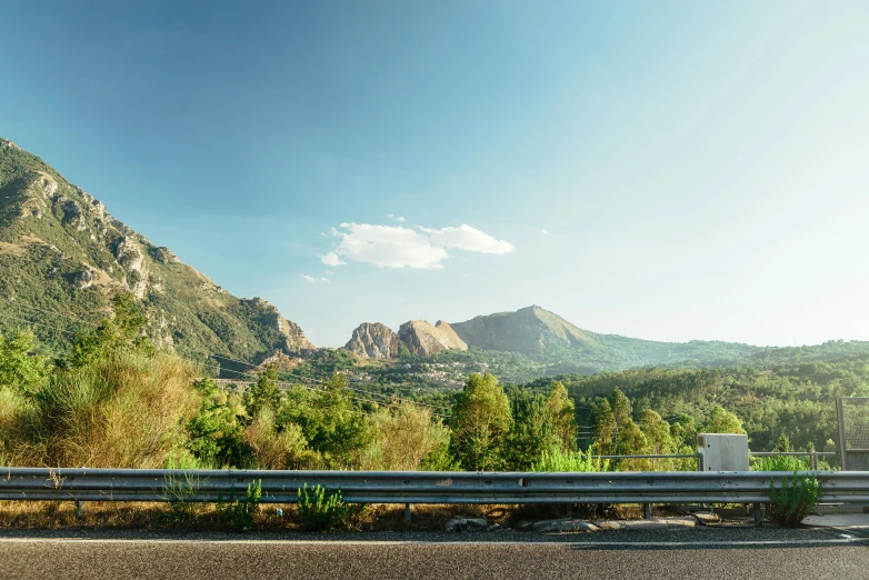 a car driving past a lush green hillside under a blue sky