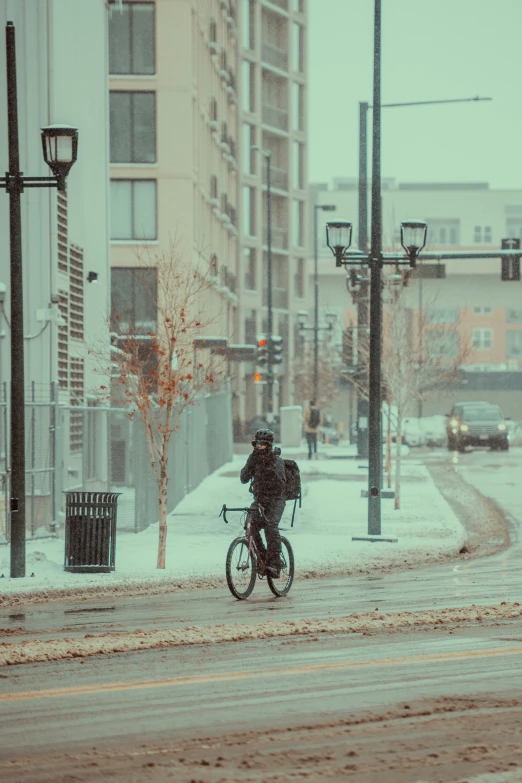 a person on a bicycle riding down the road in a snowy day