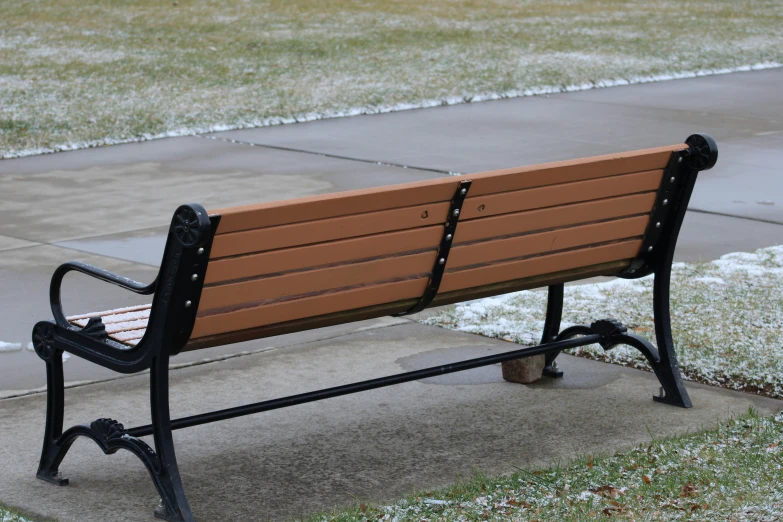 a park bench sitting on a sidewalk covered in snow