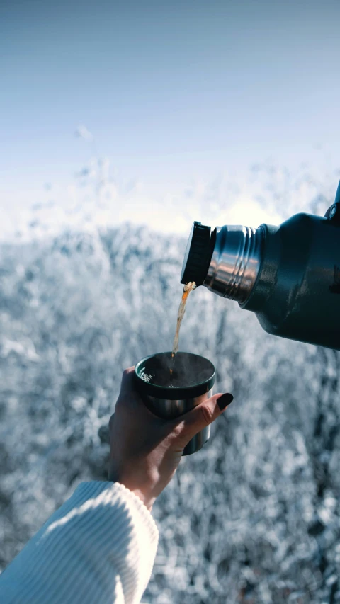 a person is standing next to some trees drinking