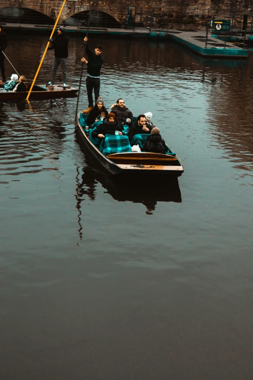 people standing on the front end of a boat as another stands on the side of a large body of water